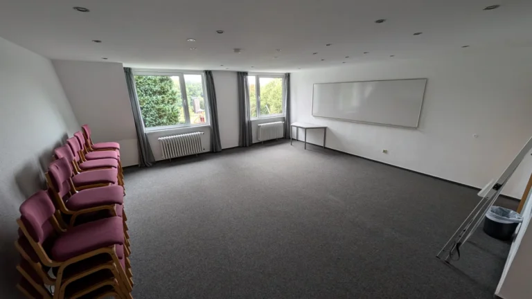Großer leerer Seminarraum mit Teppichboden und Whiteboard an der Wand – Evangelische Gesellschaft für Deutschland KdöR