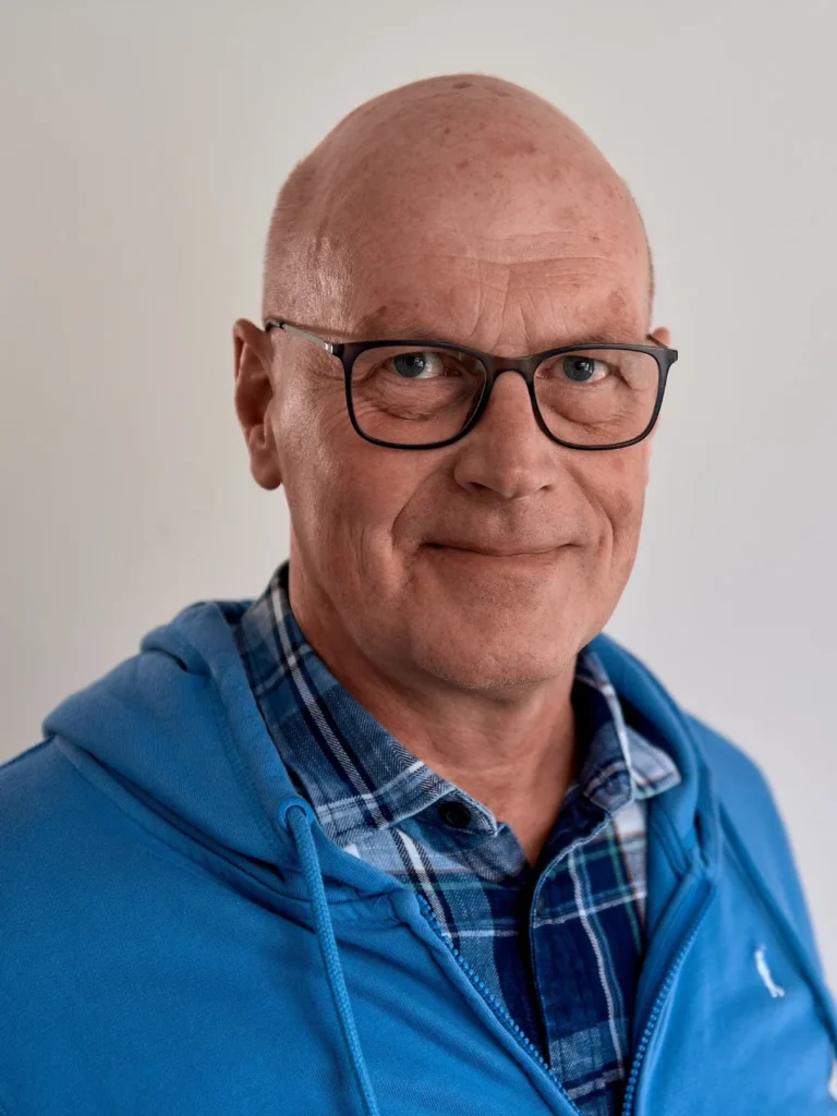 Udo Tweer - Porträt eines älteren Mannes mit Brille und blauem Oberteil vor neutralem Hintergrund – Evangelische Gesellschaft für Deutschland KdöR