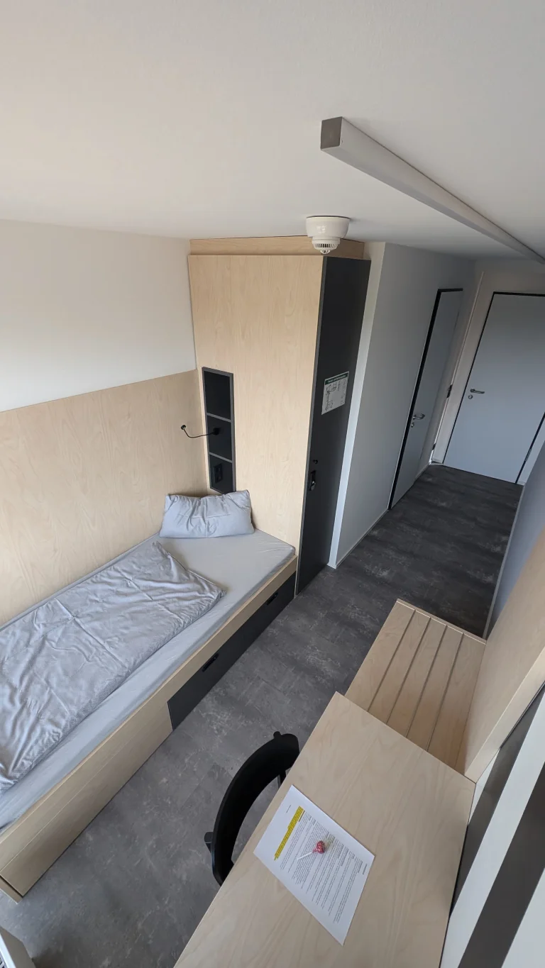 Schlafbereich mit Bett und angrenzendem Flur mit Treppe – Evangelische Gesellschaft für Deutschland KdöR