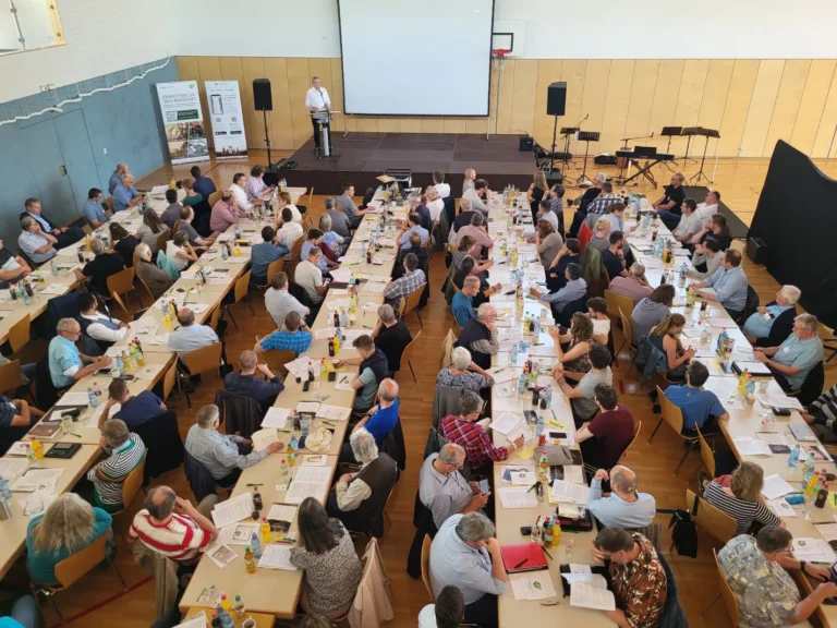 Seminar oder Tagung mit vielen Teilnehmenden an langen Tischen in einem Saal – Evangelische Gesellschaft für Deutschland KdöR