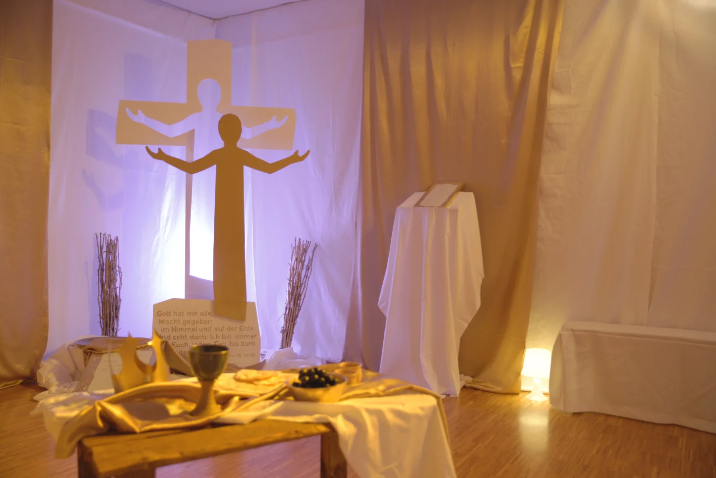Religiöse Szene mit Kreuz, Lichtinstallation und dekoriertem Tisch in warmem Licht – Evangelische Gesellschaft für Deutschland KdöR