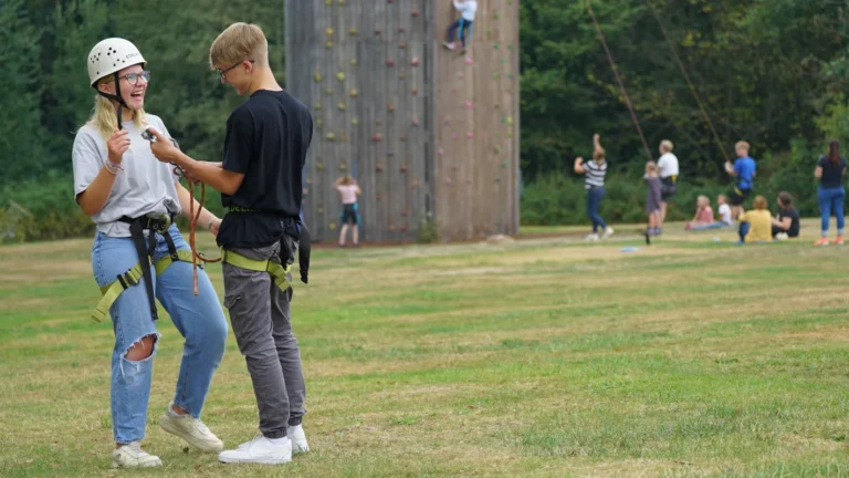 Jugendlicher beim Klettern an einer Kletterwand im Freien mit Sicherung – Evangelische Gesellschaft für Deutschland KdöR