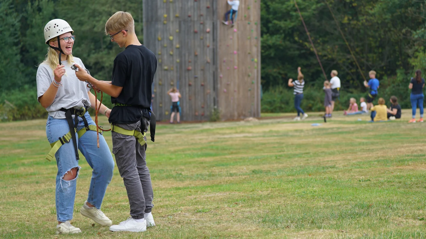 Jugendlicher beim Klettern an einer Kletterwand im Freien mit Sicherung – Evangelische Gesellschaft für Deutschland KdöR