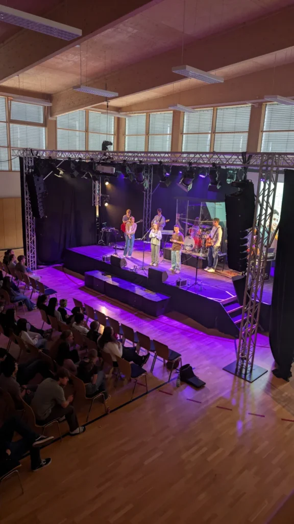 Konzert oder Bühnenaufführung mit Band unter buntem Bühnenlicht und Publikum davor – Evangelische Gesellschaft für Deutschland KdöR