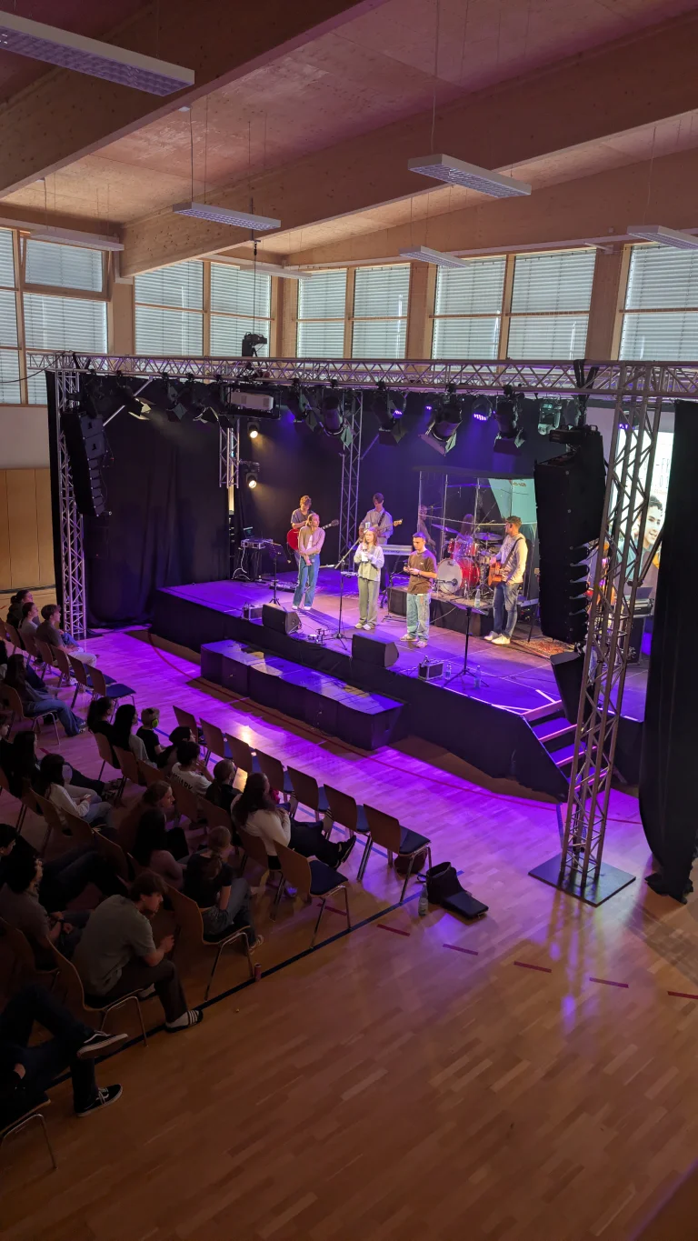 Konzert oder Bühnenaufführung mit Band unter buntem Bühnenlicht und Publikum davor – Evangelische Gesellschaft für Deutschland KdöR