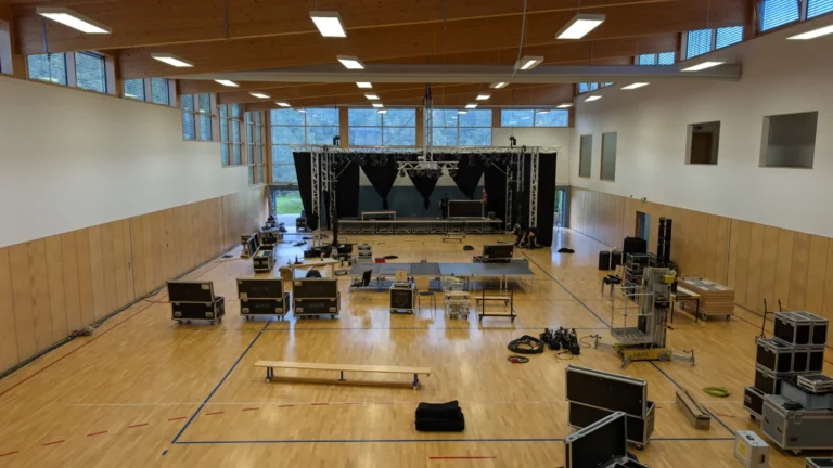 Große Mehrzweckhalle mit aufgebauter Technik, Lautsprechern und Sitzgelegenheiten – Evangelische Gesellschaft für Deutschland KdöR