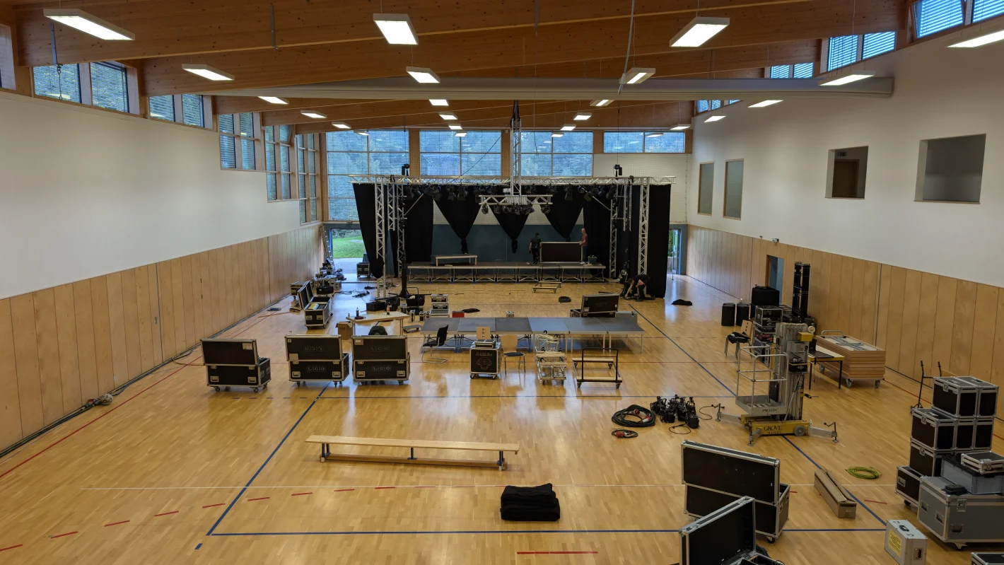 Große Mehrzweckhalle mit aufgebauter Technik, Lautsprechern und Sitzgelegenheiten – Evangelische Gesellschaft für Deutschland KdöR