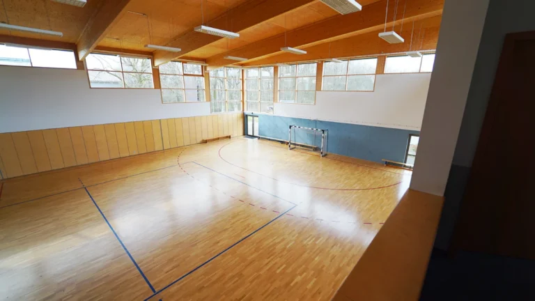 Helle Sporthalle mit Holzfußboden und großen Fenstern – Evangelische Gesellschaft für Deutschland KdöR